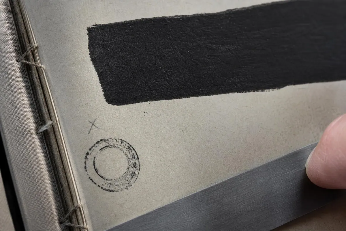 Gros plan sur une page de registre administratif relié dont plusieurs lignes sont recouvertes par un large bandeau d’encre noire